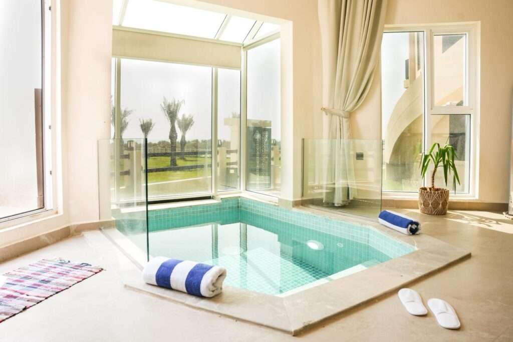 مسبح داخلي خاص بنوافذ زجاجية تطل على حديقة النخيل – Private indoor pool with glass windows overlooking the palm garden