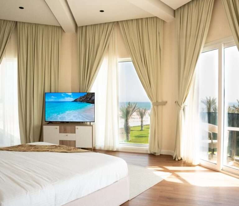 غرفة نوم بتلفاز ونوافذ واسعة تطل على الحديقة – Bedroom with TV and large windows overlooking the garden